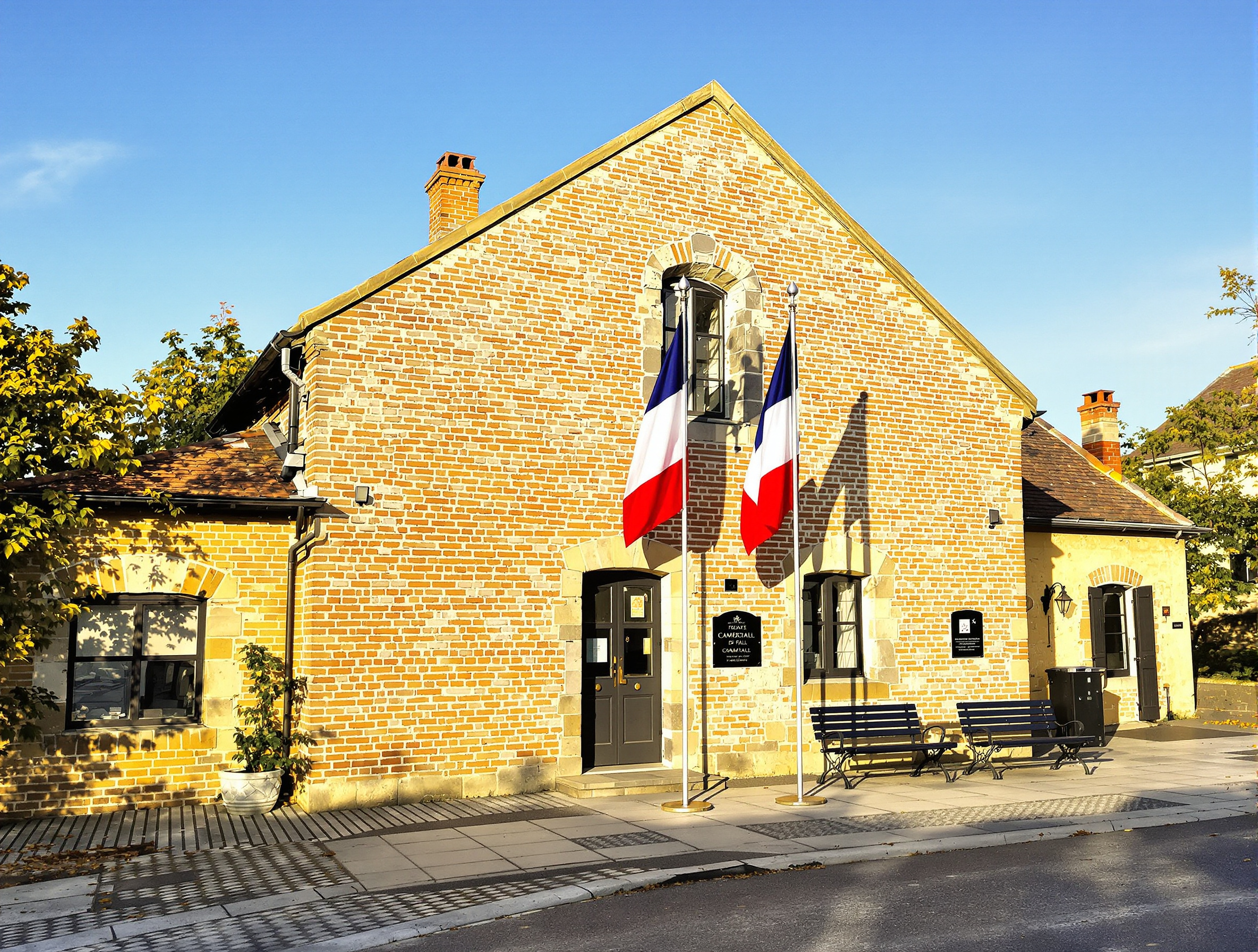 Photo de la mairie de Cambiac, petit bâtiment communal typique du Lauragais avec un drapeau et une plaque, sur la place du village.